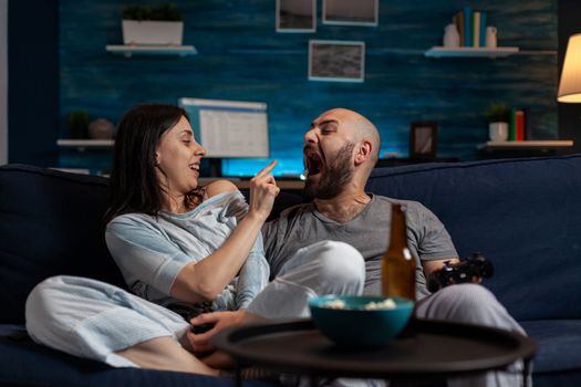 POV of happy man and woman having fun together with videogames on TV, feeling excited about leisure activity. Joyful couple using console to play competition game online on cyberspace.