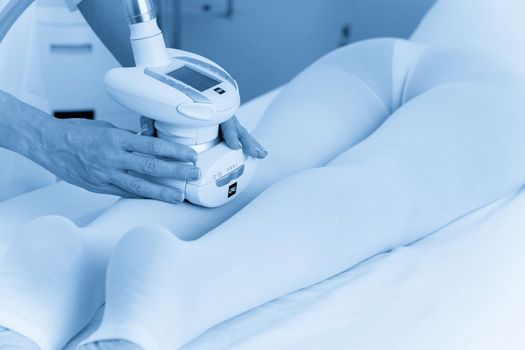 Woman in special white suit getting anti cellulite massage in a spa salon. LPG, and body contouring treatment in clinic