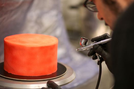 cook preparing a red frosted cake using air bush