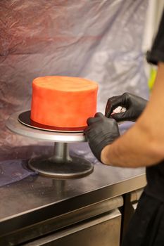 cook preparing a red frosted cake using air bush