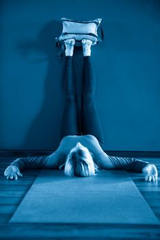 Young woman in yoga relaxing pose with legs up by a wall with heavy sand bags