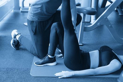 personal trainer man helping young woman in modern gym