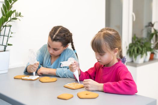 two cute sisters make and decorate cookies.