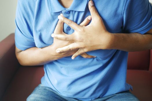 young man suffering pain in heart and holding chest with hand .