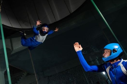 A man teaches a boy to fly in a wind tunnel. Lack of gravity