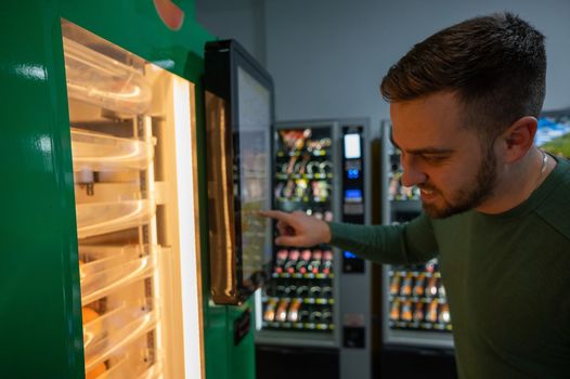 Caucasian man buys freshly squeezed orange juice from vending machine