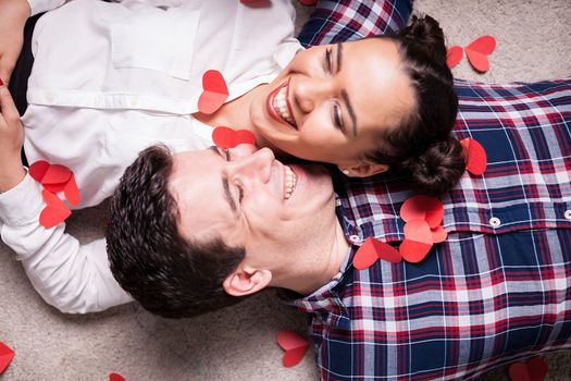 Top close up view on couple lying on the floor covered with small red hearts