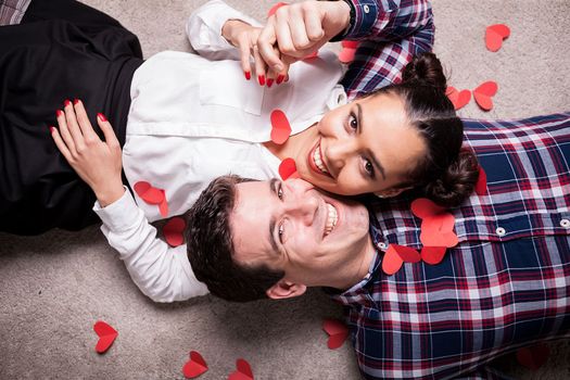 Happy man and white looking at camera while lying on the floor with small red hearts arround