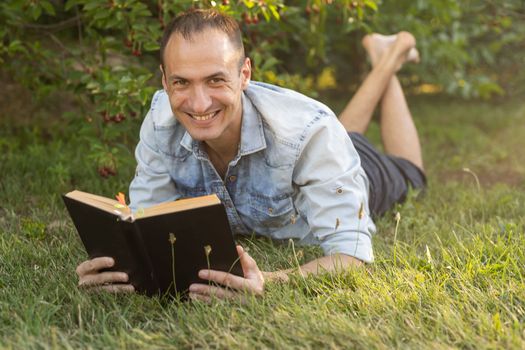 Man reading a book on the grass.
