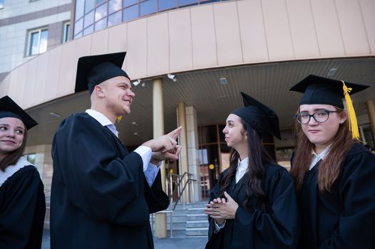 Happy students in graduate gown communicate in sign language