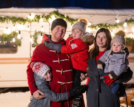 Happy large family celebrates christmas in nature and holds sparklers. Parents with three sons travels in a mobile home