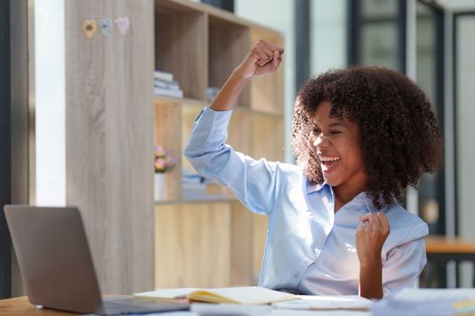 Black businesswoman work on laptop feel euphoric winning. Excited female triumph get good news from work.