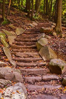 Image of Fall forest hiking trail staircase lined with stone rocks winding up