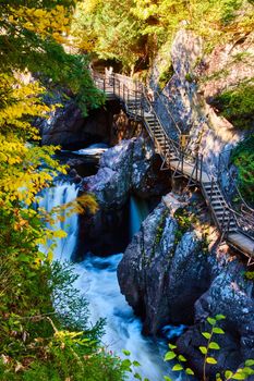 Image of Boardwalk steps built into rocky cliffs of deep gorge with rapids, waterfalls, and fall colors