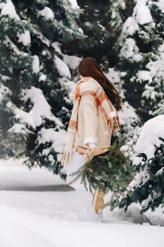 A girl in a winter forest with a bouquet of fir branches. Snowy winter.