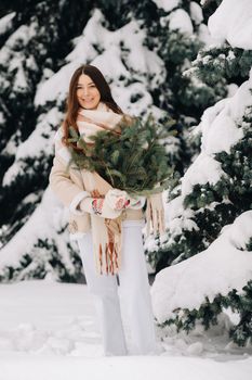 A girl in a winter forest with a bouquet of fir branches. Snowy winter.