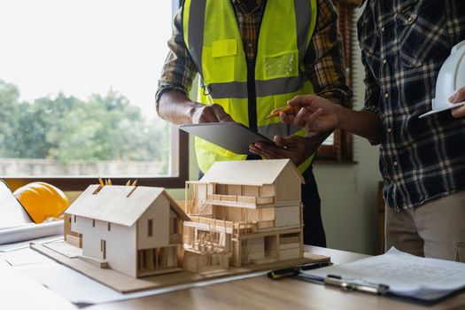 Architect team working with blueprints for architectural plan, engineer sketching a construction project, green energy concept.