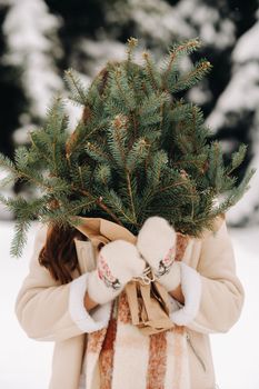 A girl in a winter forest with a bouquet of fir branches. Snowy winter.