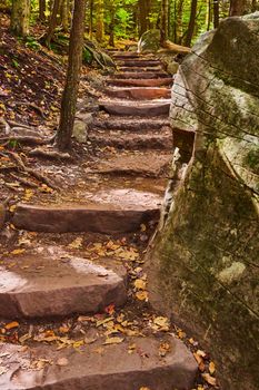 Image of Stone steps with boulders in hiking trail winding up through fall forest