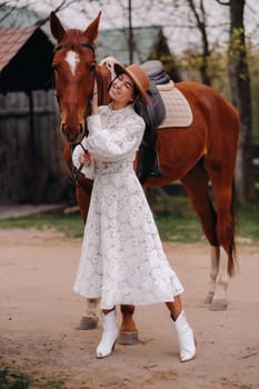 A girl in a white dress and a hat is standing next to a horse.