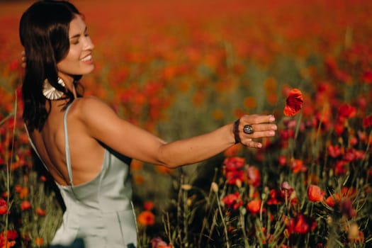 Portrait of a girl in a dress on a poppy field at sunset.