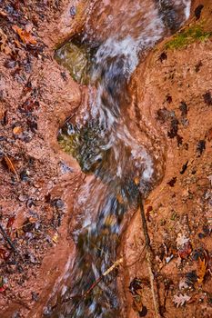 Image of River creek in clay carving wavy pattern with fall leaves from above