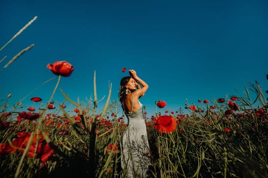 Portrait of a girl in a dress on a poppy field at sunset.