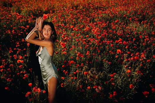 Portrait of a girl in a dress on a poppy field at sunset.