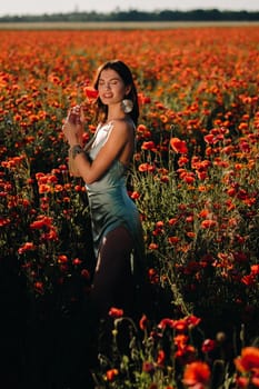 Portrait of a girl in a dress on a poppy field at sunset.