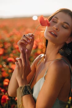 Portrait of a girl in a dress on a poppy field at sunset.