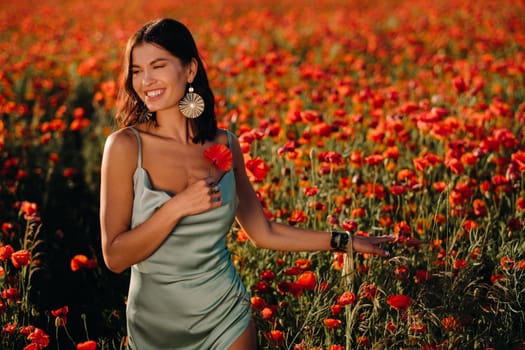 Portrait of a girl in a dress on a poppy field at sunset.