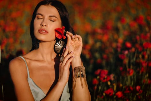 Portrait of a girl in a dress on a poppy field at sunset.