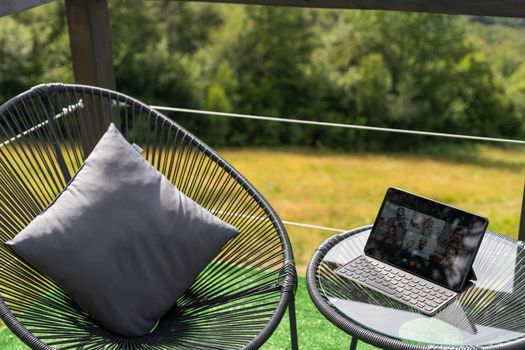 Laptop on wooden terrace, mountains and trees blurred as a background