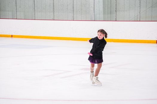 Little girl practicing before her figure skating competition at the indoor ice rink.