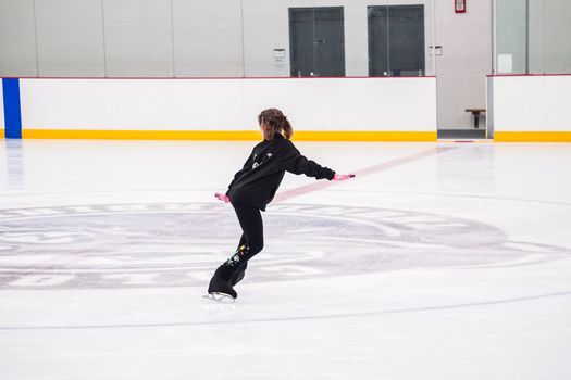 Little girl practicing figure skating at the indoor ice rink.