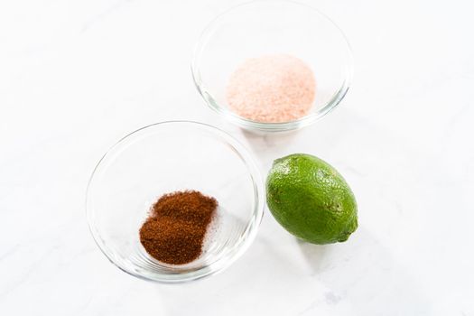 Measured ingredients in a small glass mixing bowl to prepare chili lime watermelon pops.