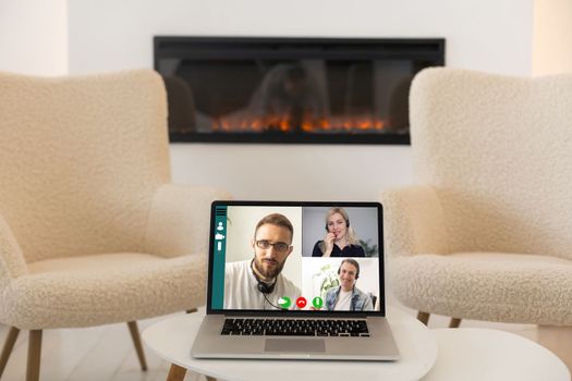 Video conference by laptop. On the laptop screen, colleagues who gathered in a video conference to work on-line. The laptop is on the work desk at home