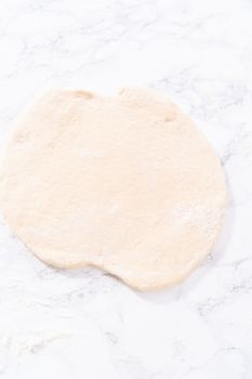 Rolling pizza dough with a french rolling pin to prepare cinnamon dessert pizza.