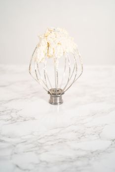 Eggnog buttercream frosting on a whisk from an electric kitchen mixer.