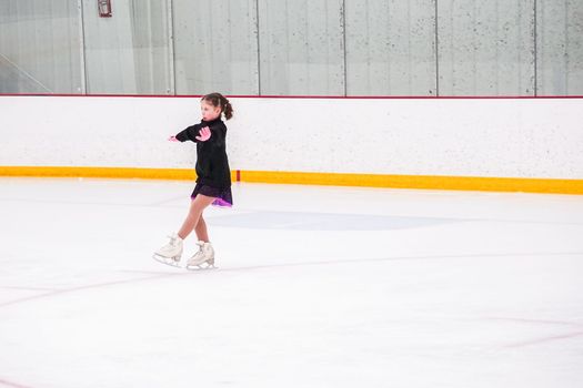 Little girl practicing before her figure skating competition at the indoor ice rink.