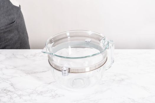 Activating dry yeast in a large glass mixing bowl to prepare the pizza dough.