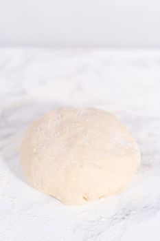 Rolling pizza dough with a french rolling pin to prepare cinnamon dessert pizza.