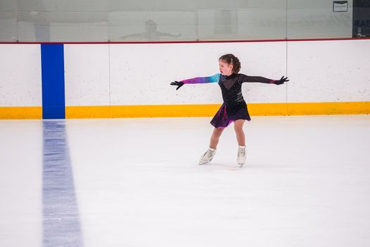 Little girl practicing before her figure skating competition at the indoor ice rink.