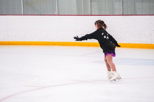 Little girl practicing before her figure skating competition at the indoor ice rink.