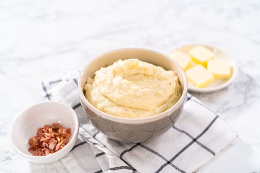 Mashed potatoes. Creamy mashed potatoes garnished with a slice of butter and bacon bits in a bowl.