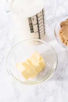 Measured ingredients in a glass mixing bowl to preparetoffee glaze.