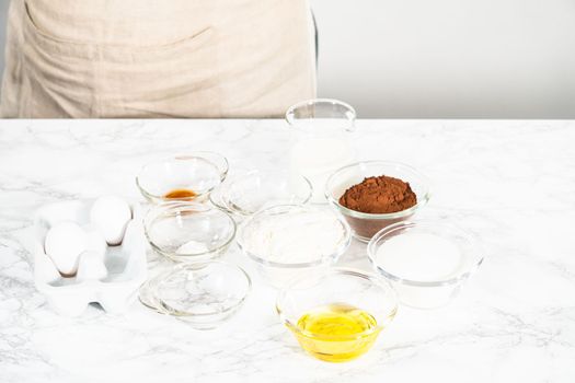 Measured ingredients in glass mixing bowls to prepare chocolate cupcake.