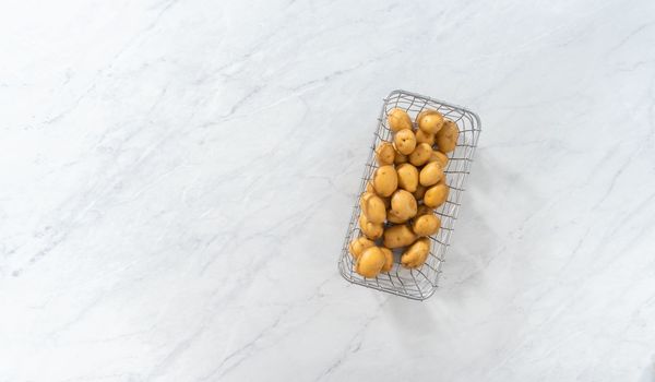 Flat lay. Pressure Cooker Baked Potatoes. Raw potatoes in a wire basket on the kitchen counter.