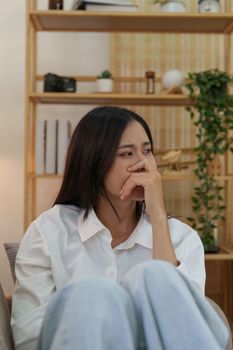 Young asian woman feeling miserable and lonely on sofa at home.