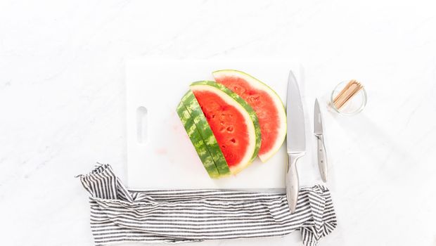Flat lay. Slicing riped red watermelon to prepare chili lime watermelon pops.